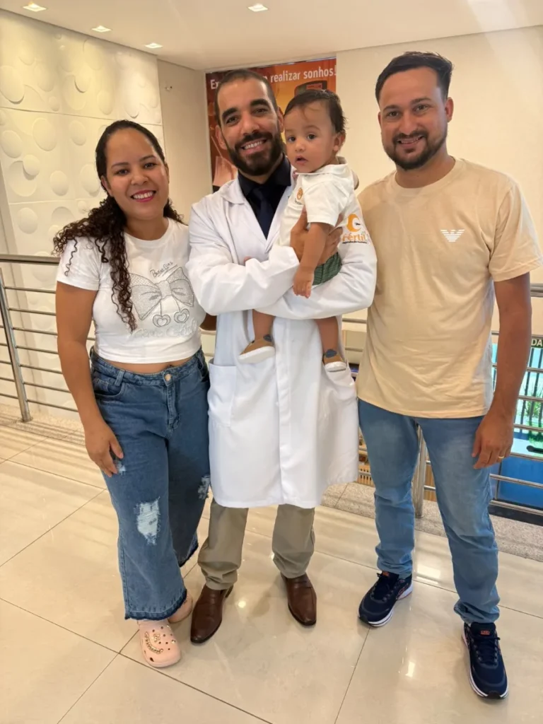 Família com bebê no colo ao lado da equipe médica da Fértil