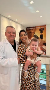 Casal com o bebê no colo ao lado de médico da Fértil