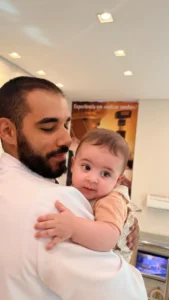 Pai com o bebê no colo sorrindo para a foto