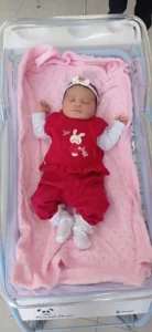 Bebê de macacão vermelho sobre manta rosa