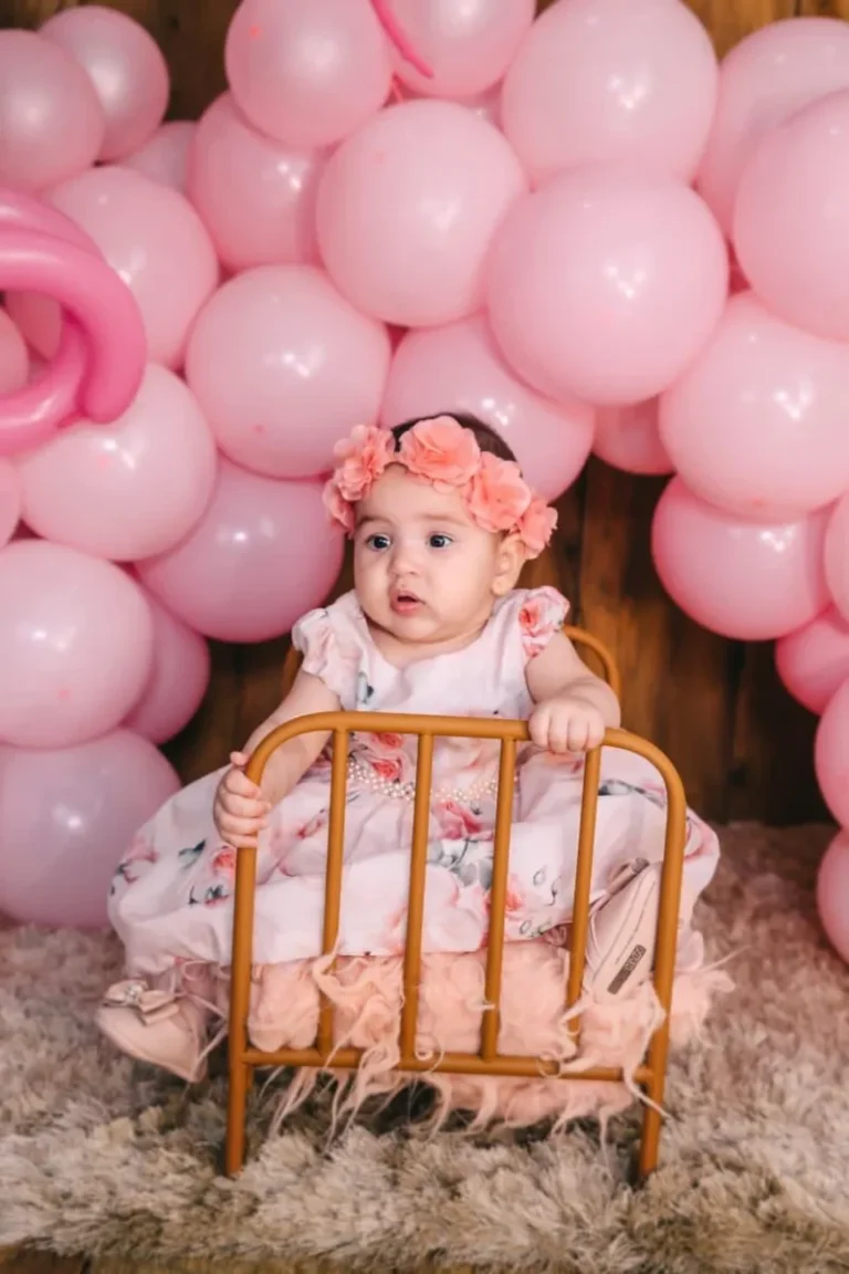 Bebê sentada em festa de aniversário com balões rosa
