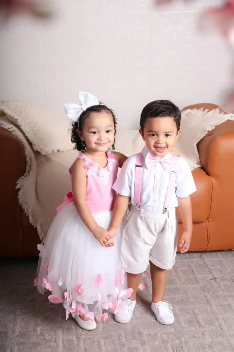 Duas crianças, menina e menino, vestidas para uma festa