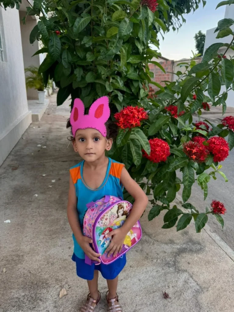 Criança com orelhas de coelho rosa em jardim de rosas