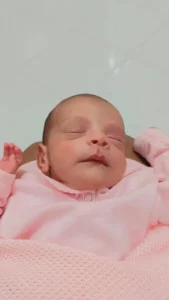 Recém-nascida dormindo em manta rosa