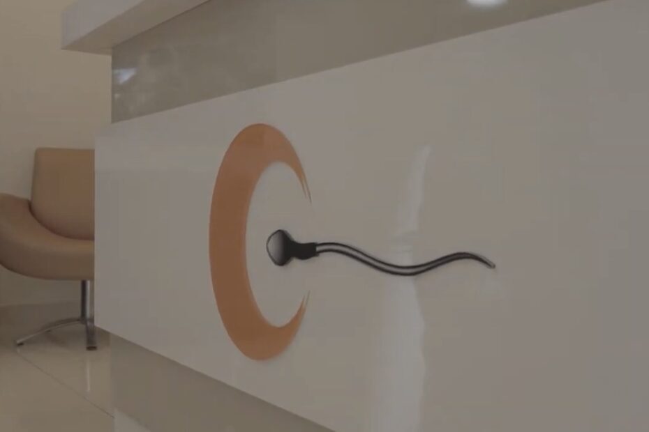 clínica de FIV: Balcão da recepção da clínica Fértil com o logotipo e a escultura de espermatozoide