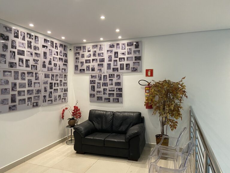 FIV em Malhada: Sala de espera no mezanino da Fértil Reprodução Humana, com sofá e mural de fotos de bebês